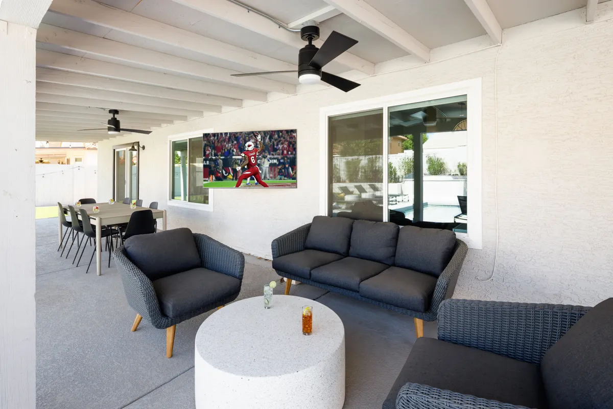 An inviting outdoor seating area with a dining table and large television sets the stage for watching sports, hosting barbecues, and socializing under open skies. The setup is ideal for group activities and connects indoor comfort with outdoor entertainment.