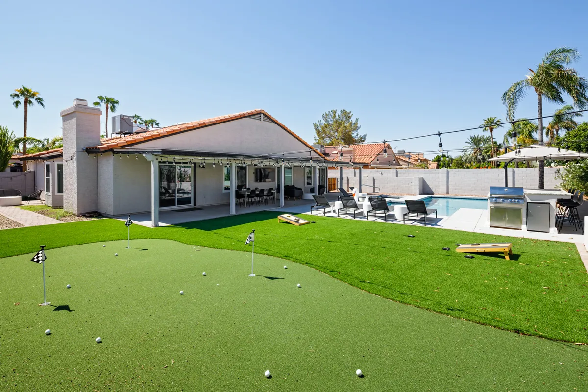 This exterior image highlights a backyard scene with a putting green, swimming pool, outdoor seating area, and a barbecue grill, set against a leisurely and social backdrop. It ties together the main amenities of the outdoor space.